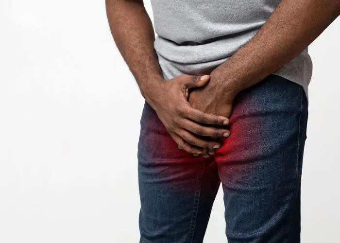 Person experiencing groin pain associated with urinary tract issues